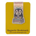 A yellow magnetic bookmark card featuring a cute cartoon penguin sitting on stacked books with a pink bow. The card reads 'Magnetic Bookmark' and shows the website 'www.