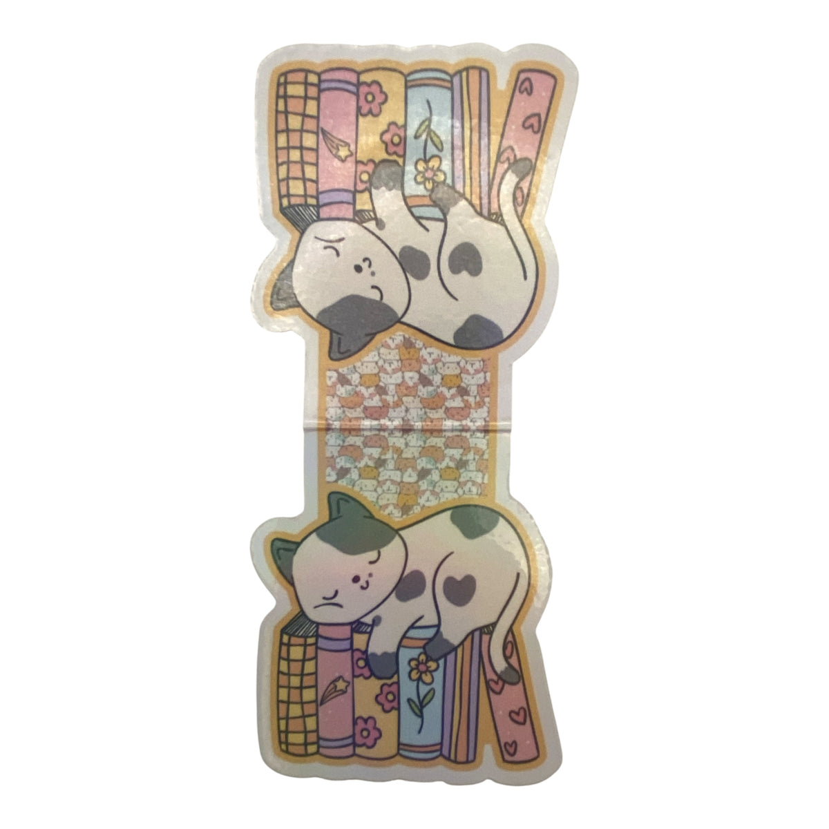 A die-cut sticker featuring two cute sleeping cats curled up on colorful patterned pillows, shown on a plain white background.