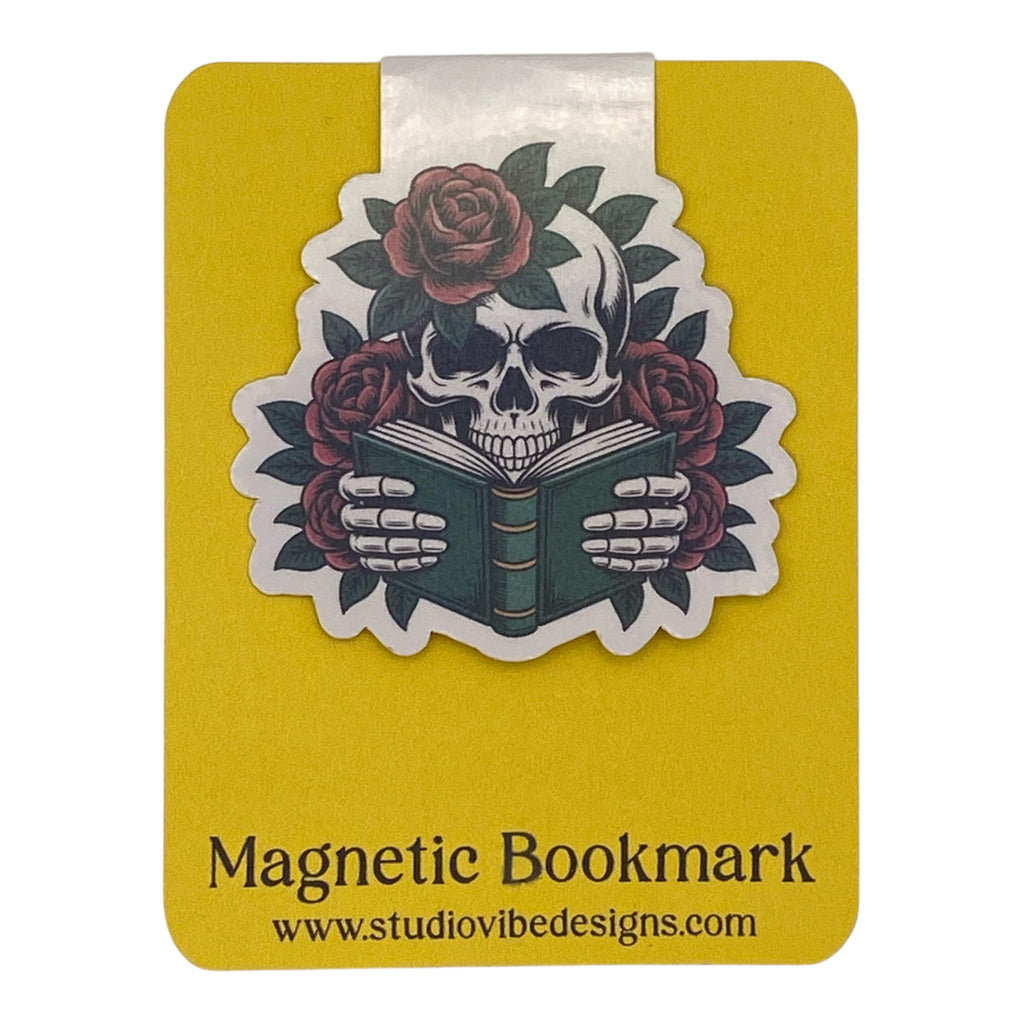 A yellow magnetic bookmark card featuring a die-cut sticker of a skull reading a book, surrounded by red roses and green leaves. The card has a white tab at the top and black text at the bottom that reads 'Magnetic Bookmark' and 'www.