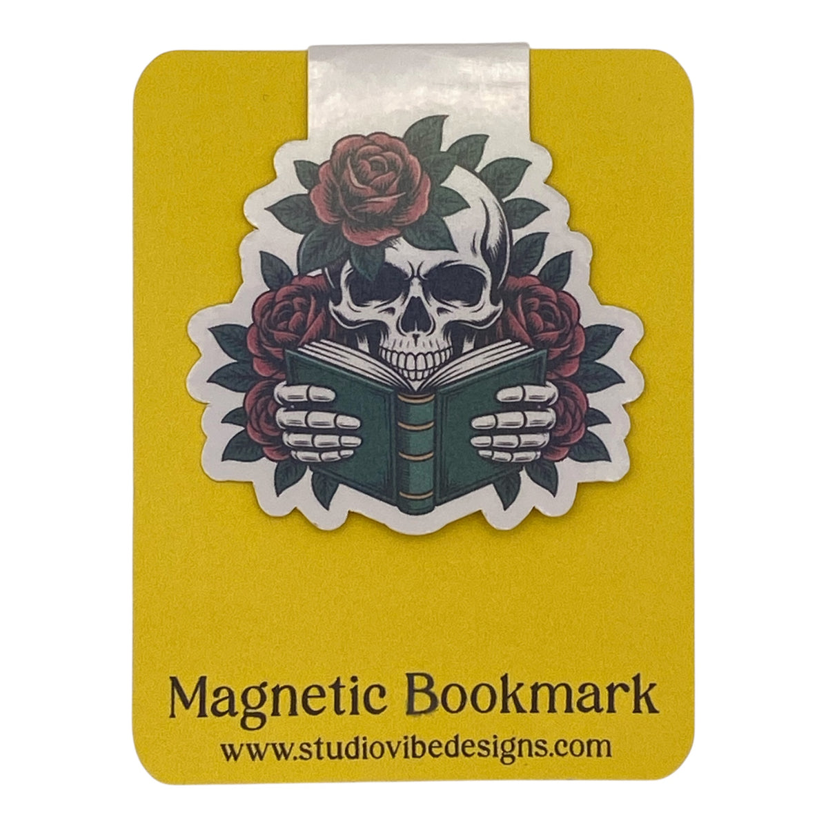 A yellow magnetic bookmark card featuring a die-cut sticker of a skull reading a book, surrounded by red roses and green leaves. The card has a white tab at the top and black text at the bottom that reads 'Magnetic Bookmark' and 'www.