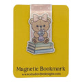 A yellow magnetic bookmark card featuring a cute teddy bear illustration sitting on stacked books with a pink bow, plus the text 'Magnetic Bookmark' and 'www.studiovibedesigns.