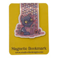 A die-cut magnetic bookmark featuring a purple cat with glasses reading a book, placed on a yellow backing card labeled 'Magnetic Bookmark' with the website www.studiovidesigns.