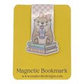 A cute die-cut magnetic bookmark of an otter holding a bubble tea cup on top of three books, attached to a yellow magnetic bookmark card. The card features the text 'Magnetic Bookmark' and the website 'www.