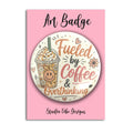 A circular art badge featuring a coffee cup illustration and the phrase 'Fueled by Coffee & Overthinking' on a pink backing card labeled 'Art Badge' and 'Studio Vibe Designs'.