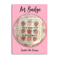 A round pin badge featuring a strawberry-themed design with the text 'LIFE IS BERRY sweet so choose happiness', mounted on a pink backing card labeled 'Art Badge' and 'Studio Vibe Designs'.