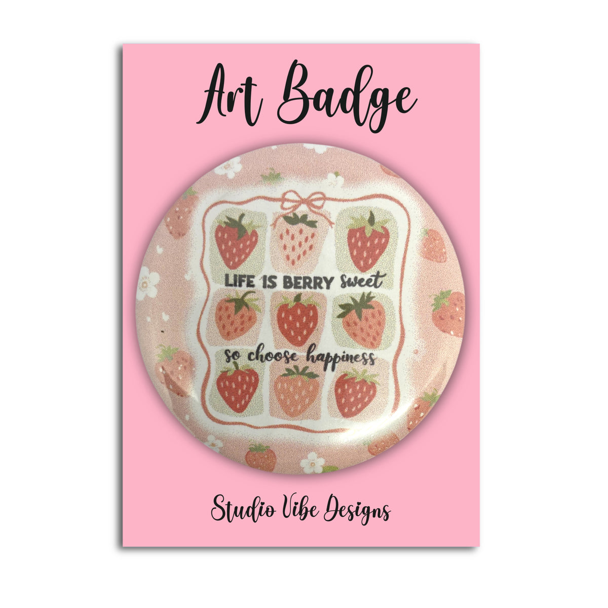 A round pin badge featuring a strawberry-themed design with the text 'LIFE IS BERRY sweet so choose happiness', mounted on a pink backing card labeled 'Art Badge' and 'Studio Vibe Designs'.