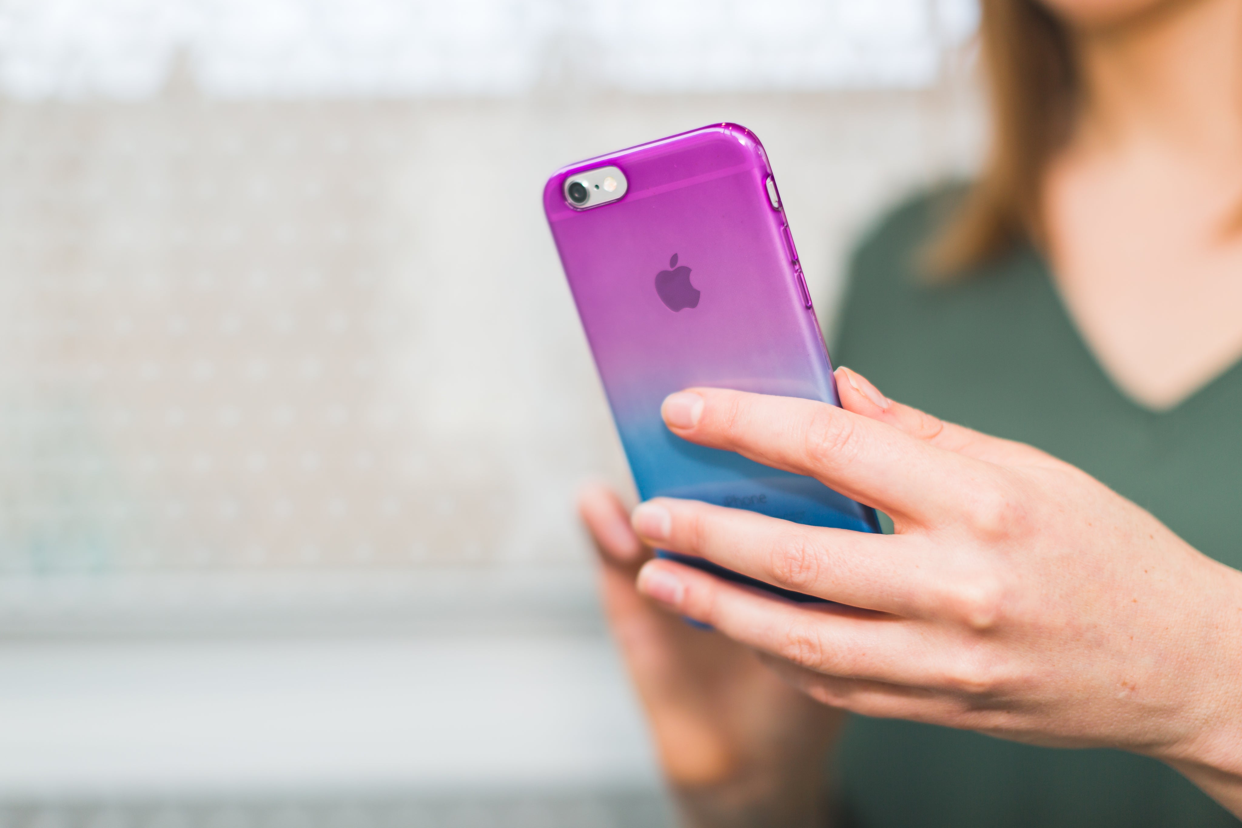 woman holding a moble phone- showing a bright and colourful phone case in hues of pink and blue